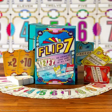 Flip 7 The game Flip 7 sits on a wooden table with a circle of Flip 7 cards around it in front of a background of Flip 7 cards