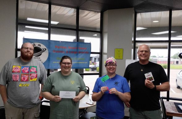 5.28.26 Trivia Night Winners Four people stand in front of a window while holding prizes